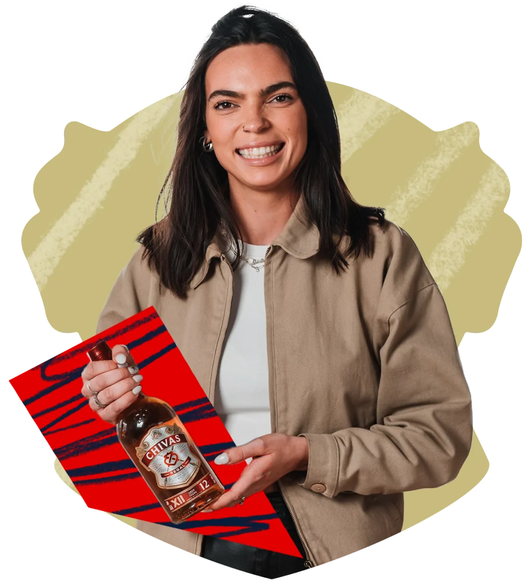 Brand Ambassador Lauren Fryer holds a bottle of Chivas Regal against a red background.