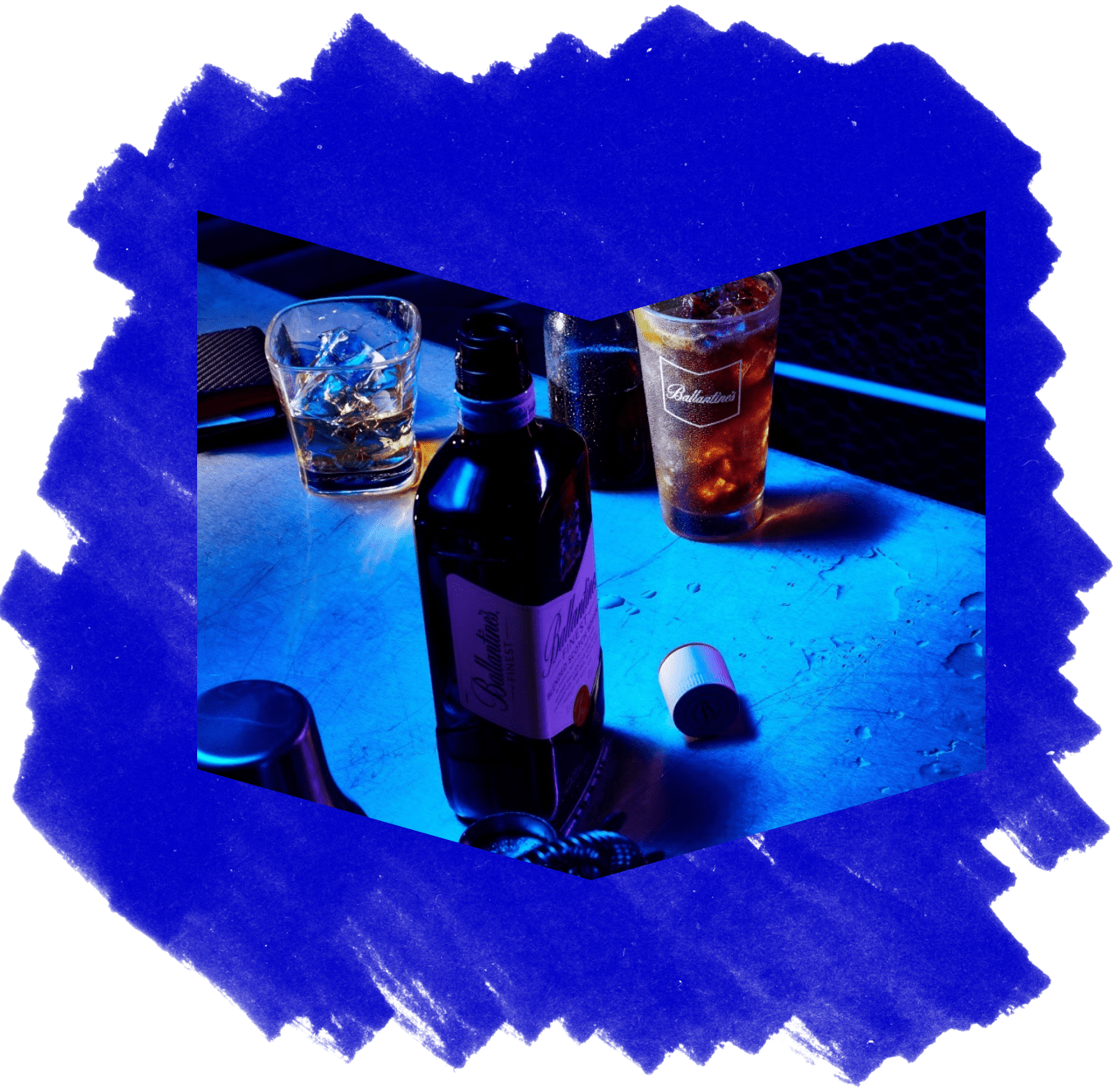 A bottle of Ballantine's whisky and glasses lit with blue light, on a blue textured background.