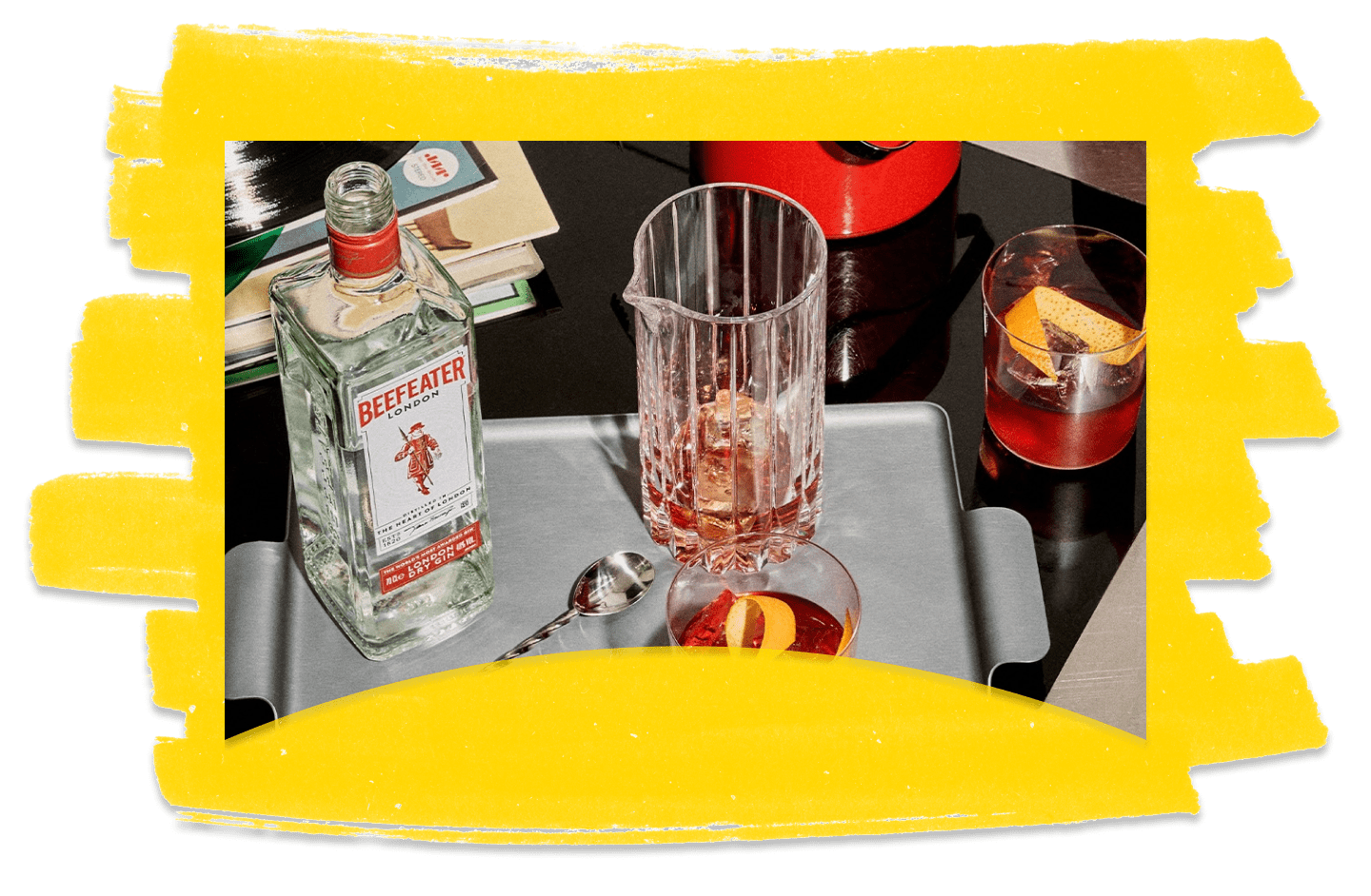 A bottle of Beefeater gin and cocktail glasses against a yellow textured background.